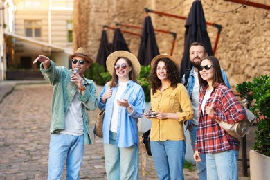 Photo of Guide with microphone and group of tourists on city street during excursion