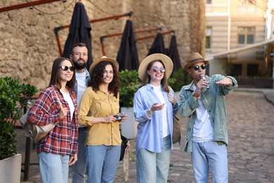 Photo of Guide with microphone and group of tourists on city street during excursion