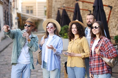 Photo of Guide with microphone and group of tourists on city street during excursion