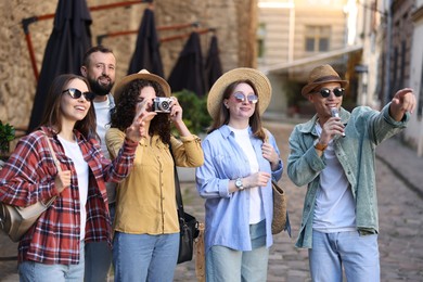 Photo of Guide with microphone and group of tourists on city street during excursion