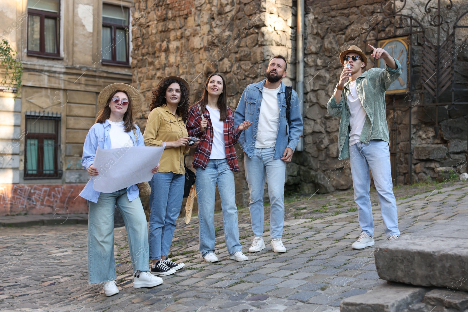 Guide with microphone and group of tourists on city street during excursion Photo of Guide with microphone and group of tourists on city street during excursion