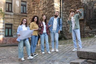 Photo of Guide with microphone and group of tourists on city street during excursion