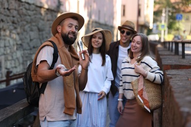 Photo of Guide with microphone and tourists on city street during excursion