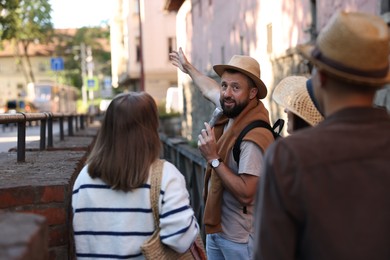 Photo of Guide with microphone and tourists on city street during excursion