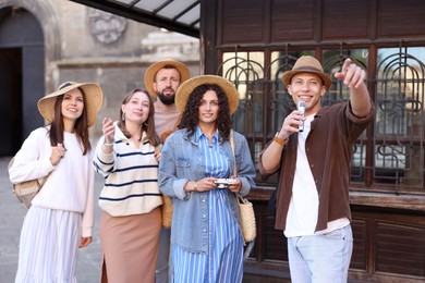 Photo of Guide with microphone and group of tourists on city street during excursion