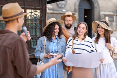 Photo of Guide with microphone and group of tourists on city street during excursion