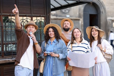 Photo of Guide with microphone and group of tourists on city street during excursion
