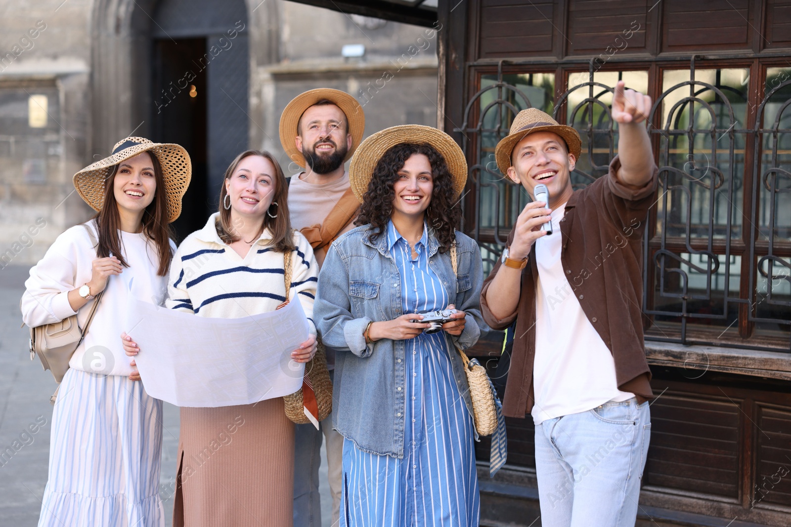 Guide with microphone and group of tourists on city street during excursion Photo of Guide with microphone and group of tourists on city street during excursion
