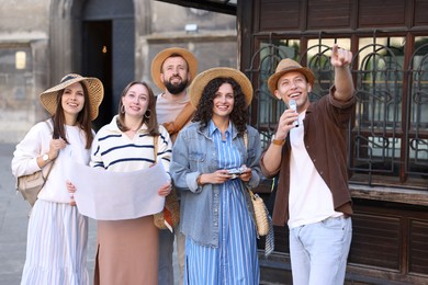 Photo of Guide with microphone and group of tourists on city street during excursion