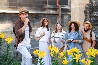 Photo of Guide with microphone and group of tourists on city street during excursion