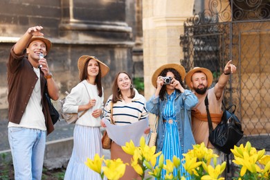Photo of Guide with microphone and group of tourists on city street during excursion