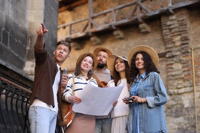 Photo of Guide with microphone and group of tourists on city street during excursion, low angle view