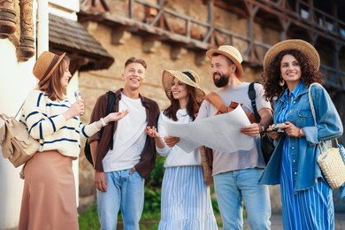 Photo of Guide with microphone and group of tourists on city street during excursion, low angle view
