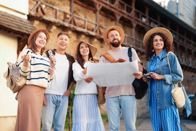 Photo of Guide with microphone and group of tourists on city street during excursion, low angle view
