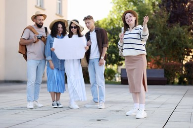 Photo of Guide with microphone and group of tourists on city street during excursion