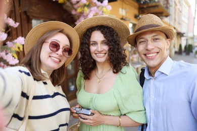 Photo of Tourists in straw hats taking selfie on city street