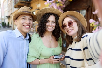 Photo of Tourists in straw hats taking selfie on city street
