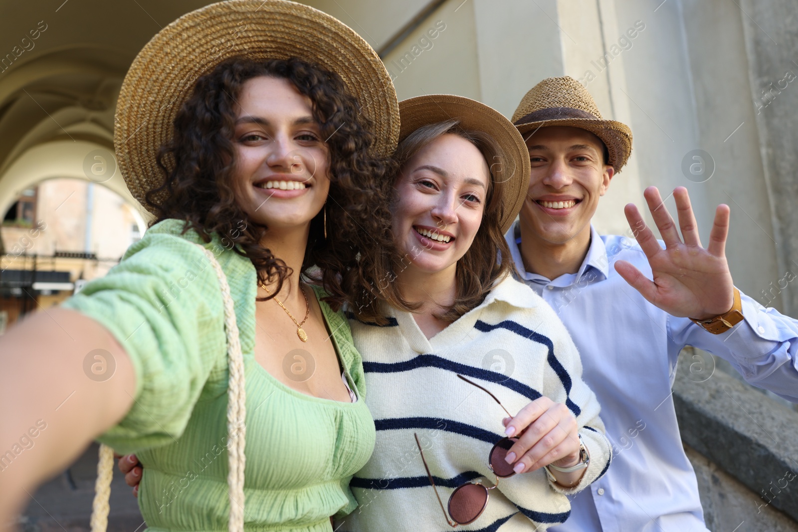 Tourists in straw hats taking selfie on city street Photo of Tourists in straw hats taking selfie on city street