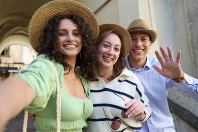 Photo of Tourists in straw hats taking selfie on city street