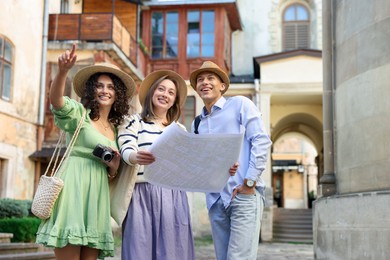 Photo of Tourists with map walking on city street, low angle view