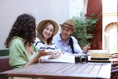 Photo of Tourists with map at wooden table on city street
