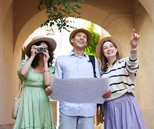 Photo of Tourists with map walking on city street, low angle view