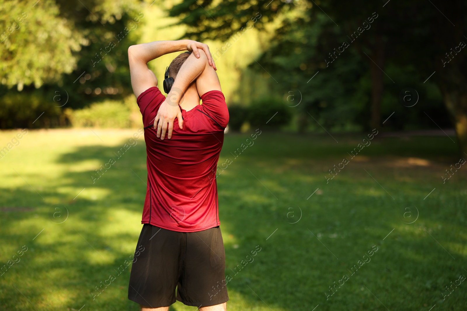 Photo of Sportsman doing morning exercise outdoors, back view. Space for text