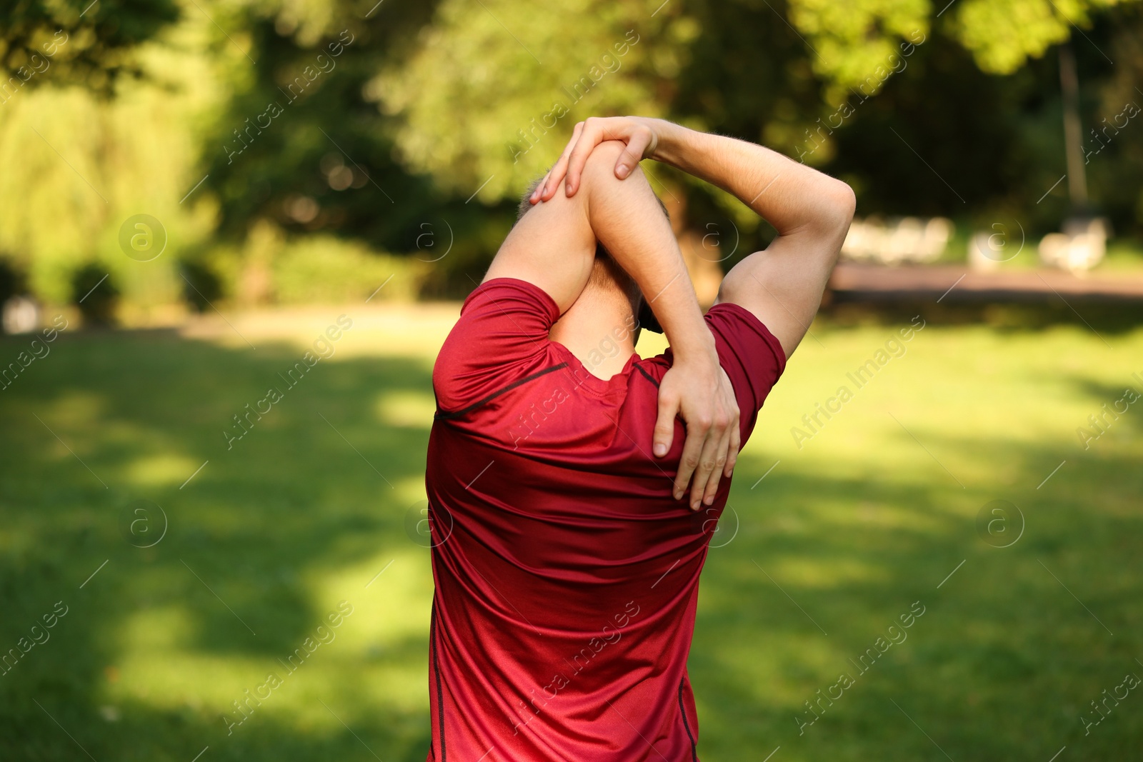 Photo of Sportsman doing morning exercise outdoors, back view