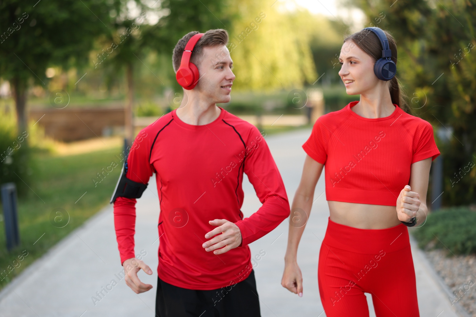 Photo of Happy couple in headphones running outdoors. Morning exercise