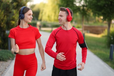 Photo of Happy couple in headphones running outdoors. Morning exercise