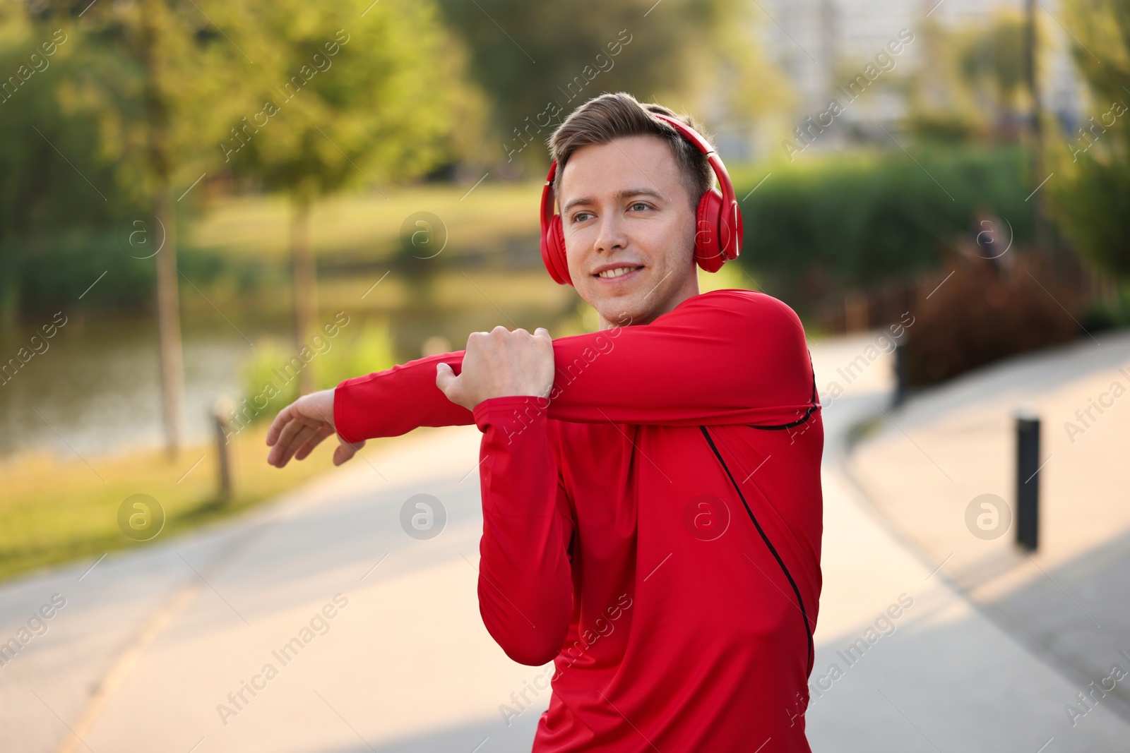 Photo of Smiling sportsman in headphones doing morning exercise outdoors. Healthy lifestyle
