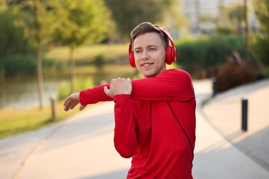 Photo of Smiling sportsman in headphones doing morning exercise outdoors. Healthy lifestyle