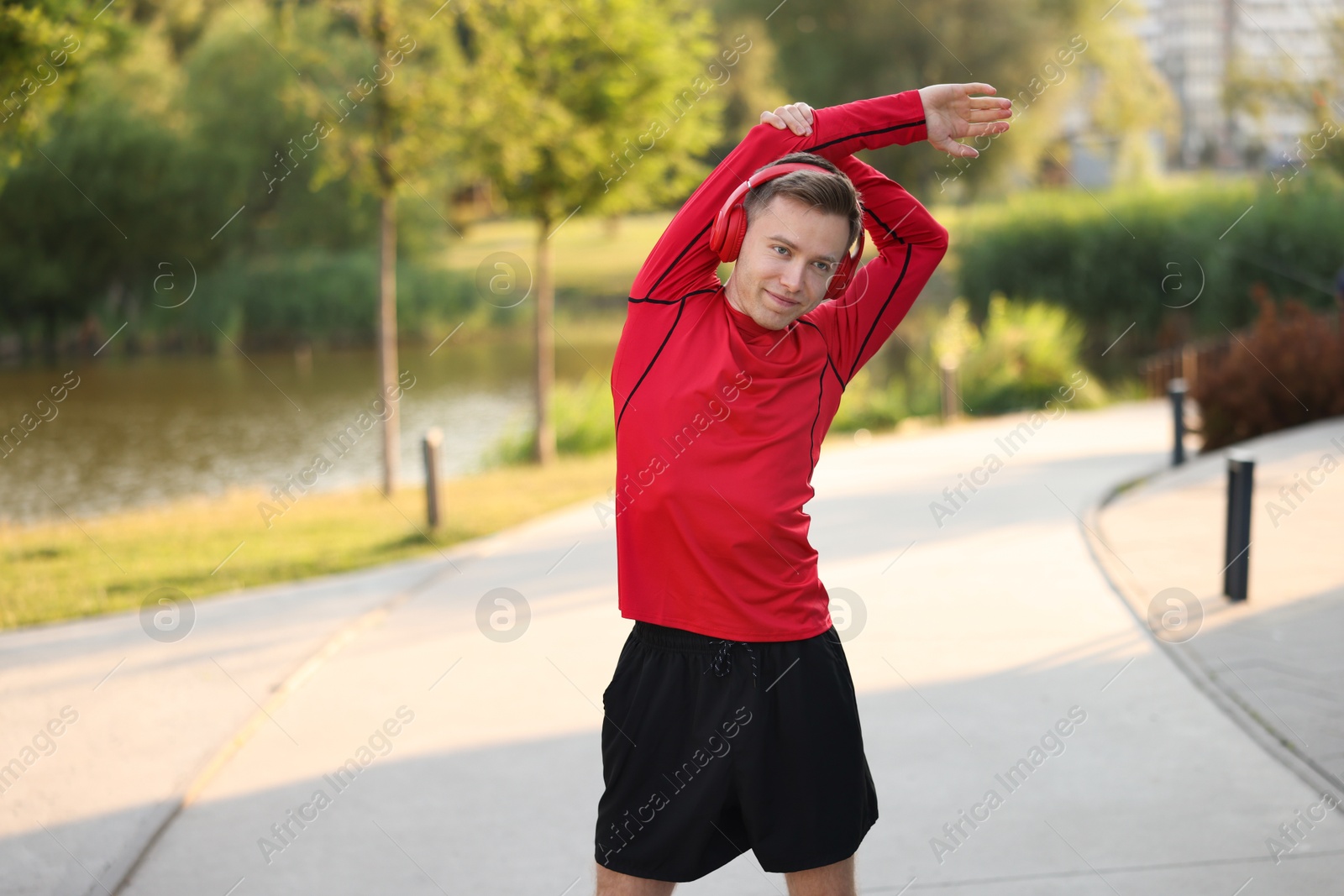 Photo of Young sportsman in headphones doing morning exercise outdoors. Healthy lifestyle