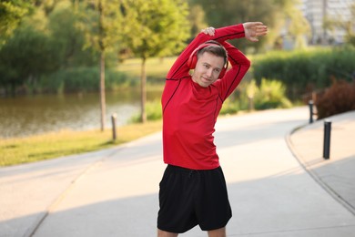 Photo of Young sportsman in headphones doing morning exercise outdoors. Healthy lifestyle