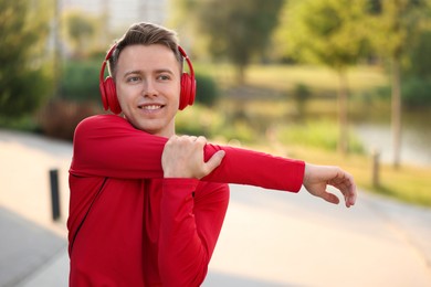 Photo of Smiling sportsman in headphones doing morning exercise outdoors. Healthy lifestyle