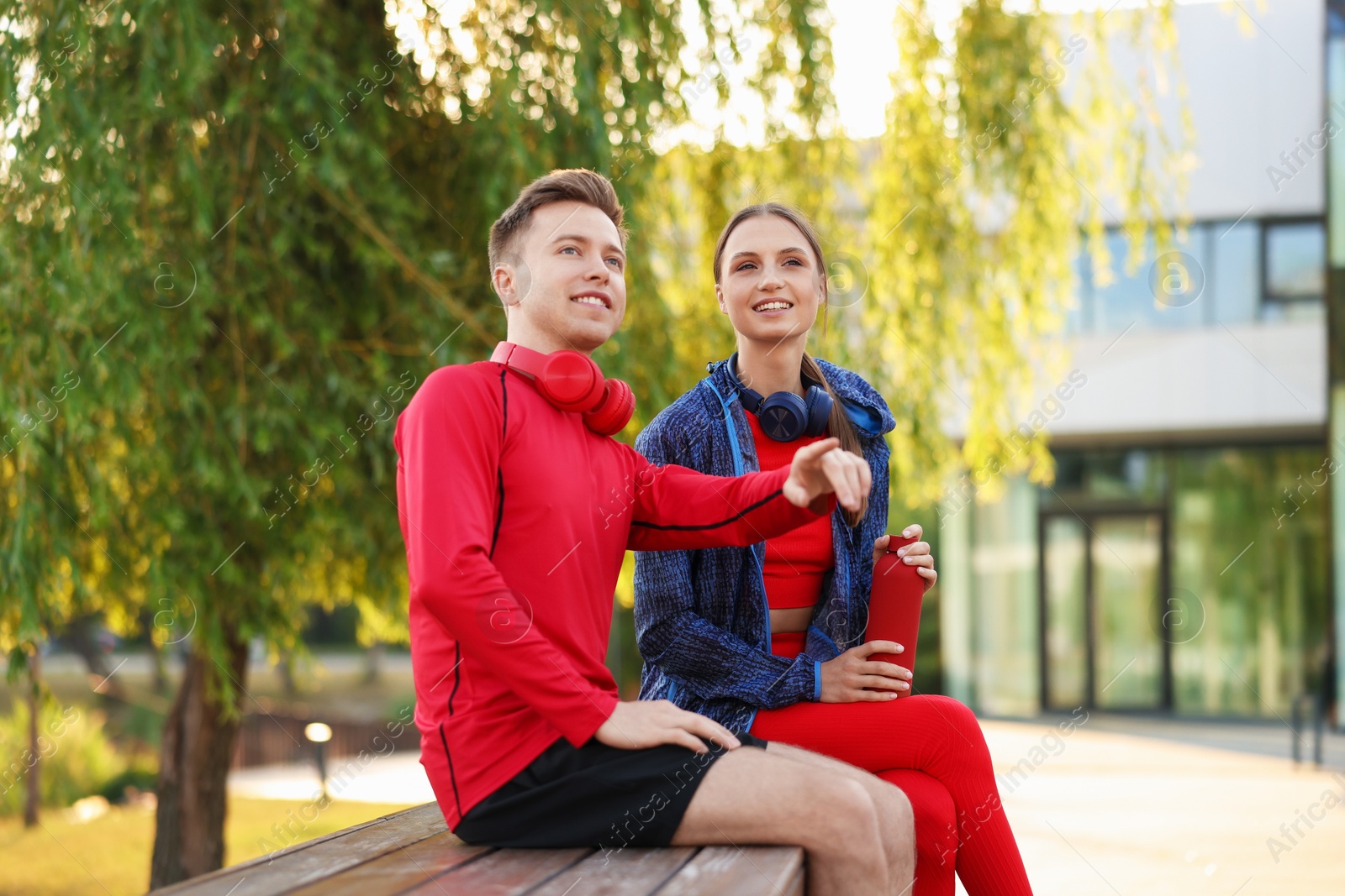 Photo of Happy couple resting on bench after morning exercises outdoors