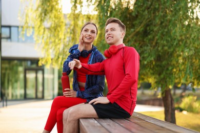 Photo of Happy couple resting on bench after morning exercises outdoors