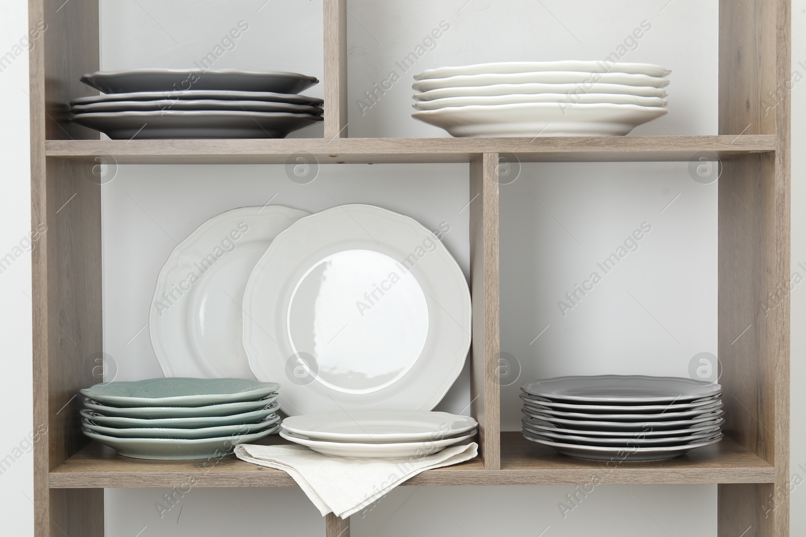 Photo of Shelving unit with different plates near white wall indoors