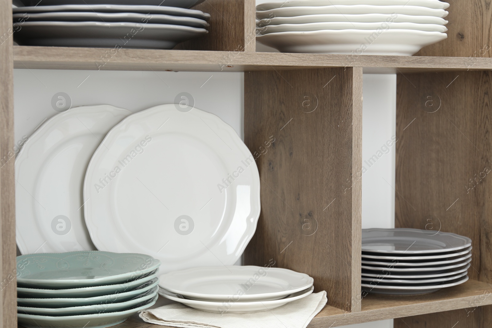 Photo of Shelving unit with different plates near white wall indoors, closeup