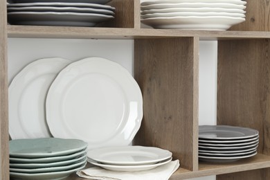 Photo of Shelving unit with different plates near white wall indoors, closeup