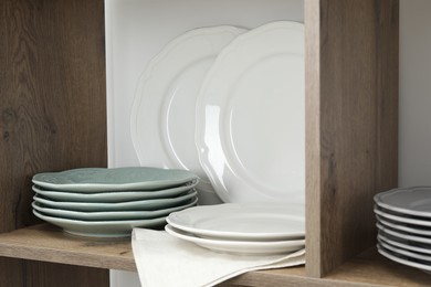 Photo of Shelving unit with different plates near white wall indoors, closeup