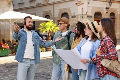 Photo of Guide with headset and group of tourists on city street during excursion