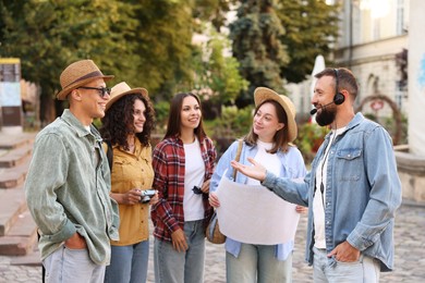 Photo of Guide with headset and group of tourists on city street during excursion