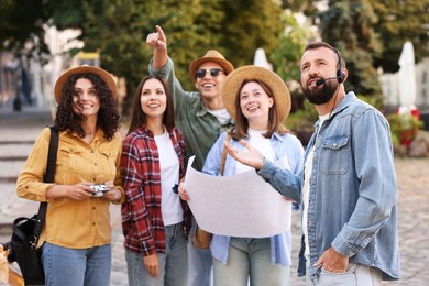 Photo of Guide with headset and group of tourists on city street during excursion
