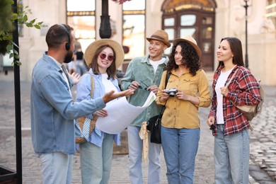 Photo of Guide with headset and group of tourists on city street during excursion