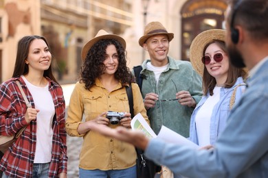 Photo of Guide with headset and group of tourists on city street during excursion