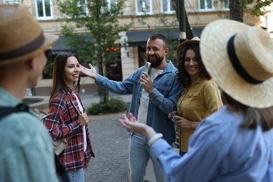 Photo of Guide with microphone and group of tourists on city street during excursion