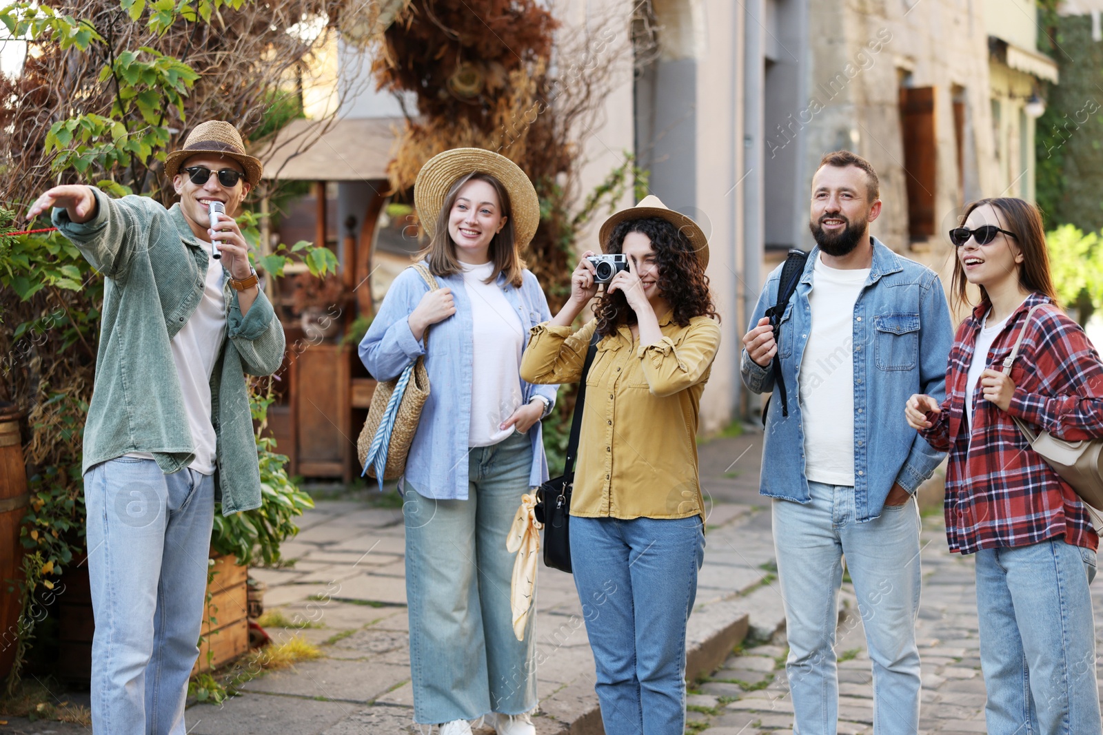 Guide with microphone and group of tourists on city street during excursion Photo of Guide with microphone and group of tourists on city street during excursion