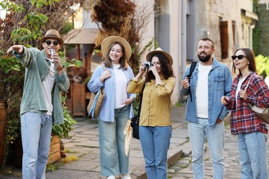 Photo of Guide with microphone and group of tourists on city street during excursion