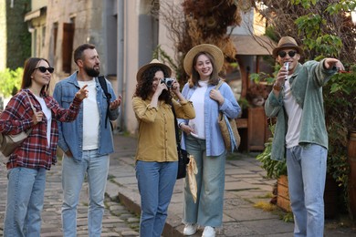 Photo of Guide with microphone and group of tourists on city street during excursion